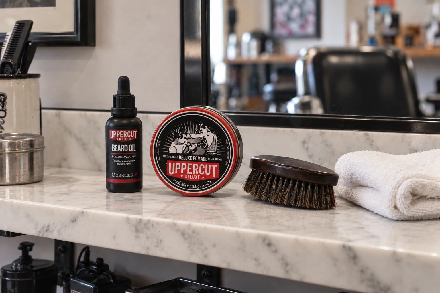 Uppercut Deluxe pomade, beard oil, beard brush and a towel on marble